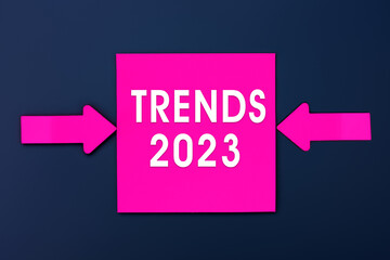 TRENDS 2023 - inscription of a magenta paper notes and two colorful arrows over a dark blue background. Top view. Business management, Inspiration to success ideas