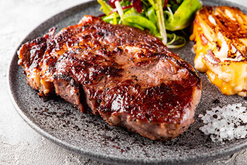 Grilled Ribeye Steak on plate with cheese and salad