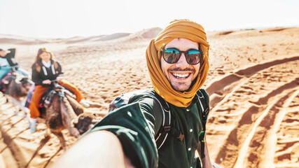 Happy tourist having fun enjoying group camel ride tour in the desert - Travel, life style,...