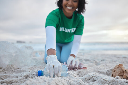 Hand, bottle and a volunteer woman on the beach for community, charity or activism during a clean up. Cleaning, environment and plastic with a female picking up plastic litter or polution on a coast