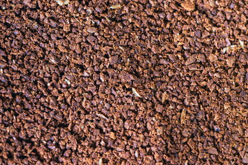 The grains of ground black coffee are very close. Close up ground coffee background. Brown coffee powder texture extreme closeup photo