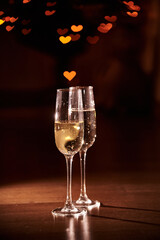 Two glasses of champagne on a dark background with blurred hearts. The concept of Valentine's Day. Overlay for your design with copy space. High quality photo