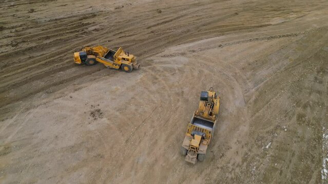 Two wheel tractor scrappers are levelling the ground of a future site for housing.