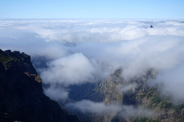Above the clouds in Madeira, with rocky mountain scenery and blue sky above.