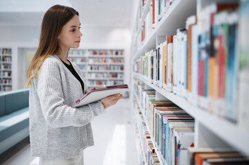 Bookshelf, student or woman in library search for research, education or learning on tablet....