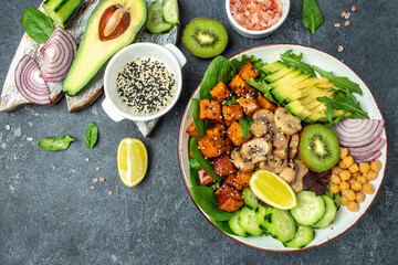 Healthy vegetable lunch in a Buddha bowl with tofu, avocado, chickpeas, cucumber and mushrooms, banner, menu, recipe place for text, top view