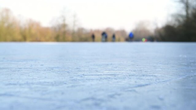 People ice skating on a frozen lake during a beautiful winter day in The Netherlands