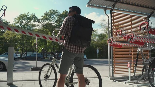 Bicycle infrastructure. A man uses double decker bicycle parking lot in Munich, Germany. The male parks his bicycle in twice-decker bicycle parking lot. Modern two level bicycle parking in Europe 
