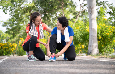 Teenager daughter take care Asian older mother with exercise walking or jogging at park