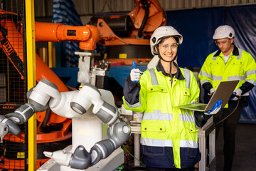 Female engineers in safety uniforms inspect the operation and maintenance of machine robots, and...
