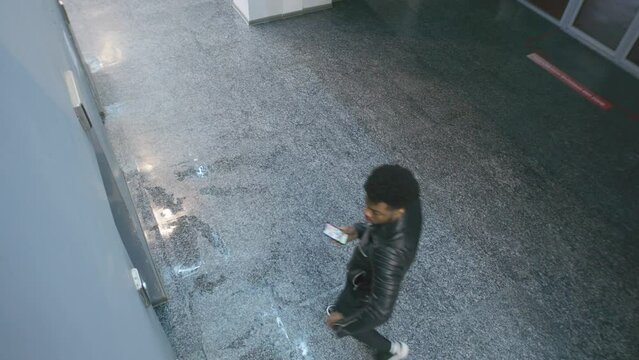 African American man tries call broken elevator at business centre, pushes call button and goes away. Observation and CCTV technologies. Concept of social safety. Privacy. Security camera shooting.