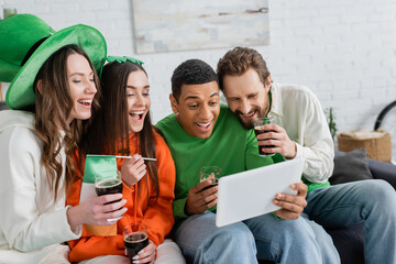 Positive multiethnic friends with beer using digital tablet at home