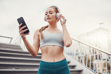 Woman, runner and phone with headphones for music, radio and web texting on chat app by stairs. Gen z girl, urban workout and fitness with smartphone for networking, social media and internet in city