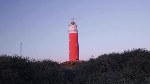Person Walking Towards Red Lighthouse On Hill At Sunset Time, Texel Island, Netherlands