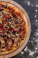 a pizza with mushrooms, peppers, and sausage on a wooden board on a table