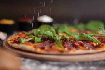 meat and green pizza pouring cheese