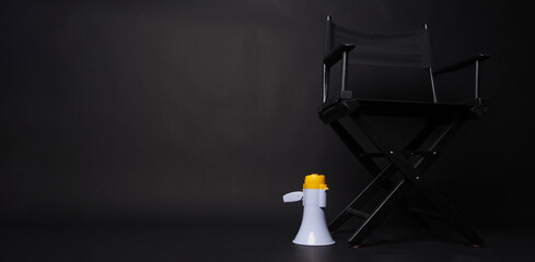 Black Director chair and megaphone on black blackground.