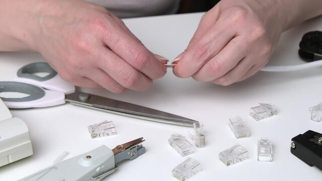 A woman's hand cuts the ends of the wire for a utp ethernet network cable plug. Internet communications concept.