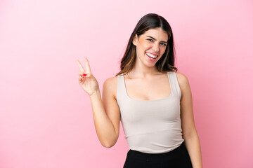 Young Italian woman isolated on pink background smiling and showing victory sign