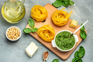 Obraz na płótnie Canvas raw Pasta tagliatelle with pesto on a dark table. italian food background, healthy food concept. Vegan or gluten free diet. top view