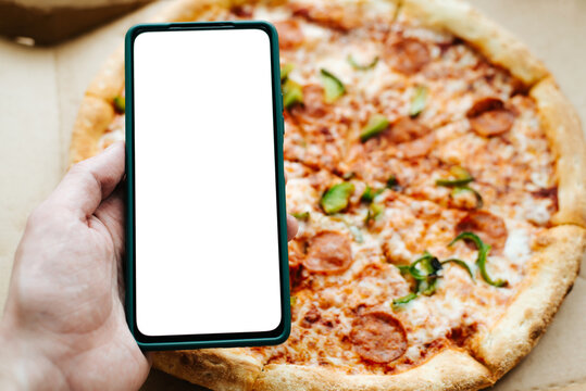 Smartphone Mockup With Blank Space For Ads And Pizza. Close-up Of Hand Holding Mobile Phone With Empty White Screen On Background Of Italian Food