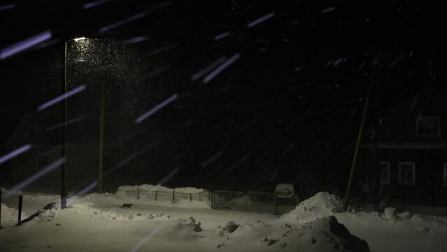  Snowstorm in night village covered with snow in winter.