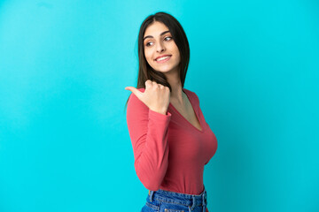 Young caucasian woman isolated on blue background pointing to the side to present a product