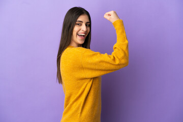 Young caucasian woman isolated on purple background doing strong gesture