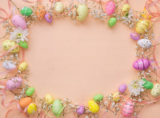 Easter background with eggs and flowers. Top view on a flat orange background. Greeting card template with a space to copy.