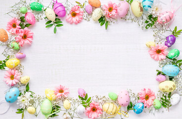 Naklejka na ściany i meble Spring Easter background with multicolored eggs and spring flowers on a wooden surface. Top view flat lay background . Greeting card pattern with copy space.