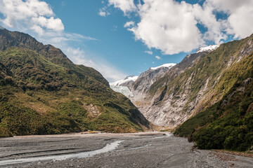 The alluvial bed of the Waiho River flowing from the Franz Josef Glacier and snow capped mountains in New Zealand - Powered by Adobe