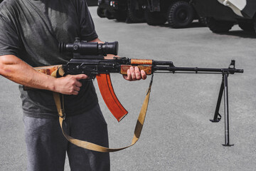 Close-up of a man holding an assault rifle with a sniper scope.
