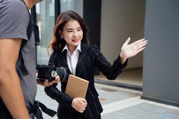 Portrait of young Asian business woman using digital tablet, professional manager holding digital tablet computer using software applications standing in front of modern business building