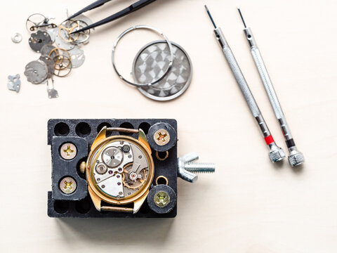 Top View Of Open Watch In Holder On Wooden Table In Watchmaker Workshop