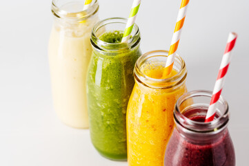 Closeup bottles with fruit smoothies. Healthy detox drinks, bright background