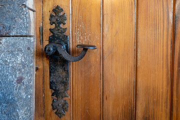 Antique iron handle worn out by the passage of time on a solid wood door. High quality photo