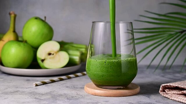 Pouring fresh green smoothie. Apple, banana, celery and spinach detox smoothie shake drink