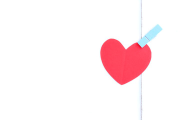 Red paper heart hanging on jute rope with wooden clothespins isolated on white background	