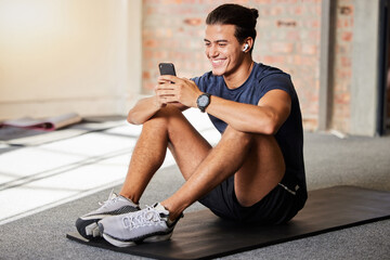 Fototapeta na wymiar Bodybuilder, gym floor and texting with smile on chat app, social media or meme on internet for happiness. Man, fitness and exercise for health, wellness or relax at training for online communication
