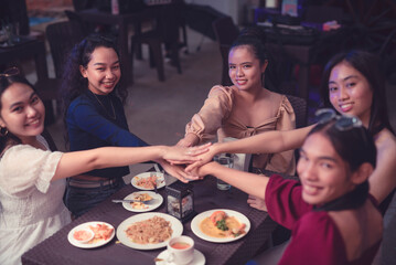 Young female millennial entrepreneurs proudly show positive relationship with a huddle while they happily smile for the camera. Ending a business meeting with a huddle.