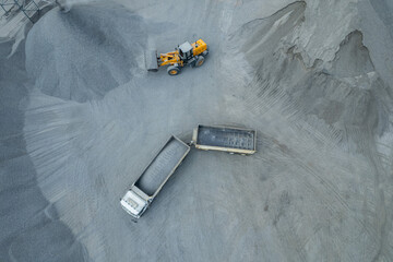 Sand loaders are shoveling rocks into dump trucks.