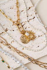 Trendy jewelry with chains, pearl necklace and pendant shapes moon and sun. Stylish golden...