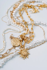 Trendy jewelry with chains, pearl necklace and pendant shapes moon and sun. Stylish golden bijouterie. Fashion accessories.