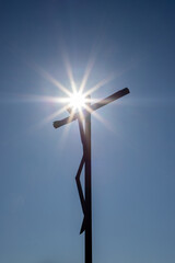 A close-up of a wooden cross representing Jesus crucified against a blue sky background