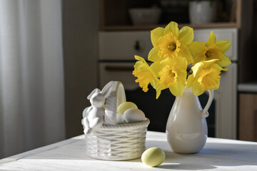 A nest with eggs in soft pastel colors and a vase of daffodils on the kitchen table. Easter still life