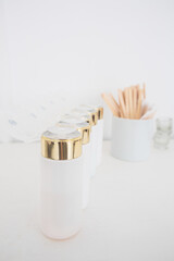 White dispenser bottles of cosmetics with golden details. close up, minimalistic. Tools for beauty, manicure, eyebrow, lash masters