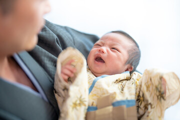 お宮参りの日に着物姿で泣いているところをお父さんに抱かれてあやされる赤ちゃん