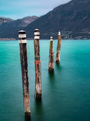 Long exposure photo of wooden bollards for mooring boats in Lago Maggiore in Locarno, Switzerland