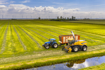Tractors on fresh mowed green agricultural grassland