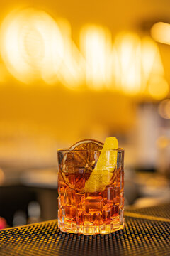 Cocktail Negroni del professore fatto con gin, vermut rosso e bitter rosso e guarnito con arancia essiccata e scorza d'arancia fresca servito in un cocktail bar serale